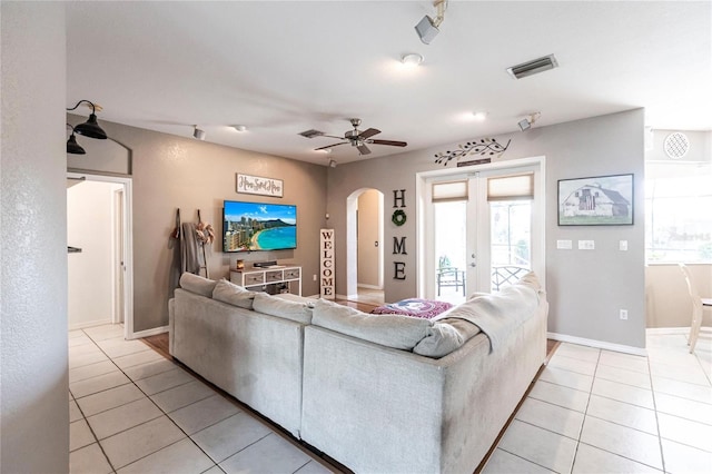 tiled living room with ceiling fan and french doors