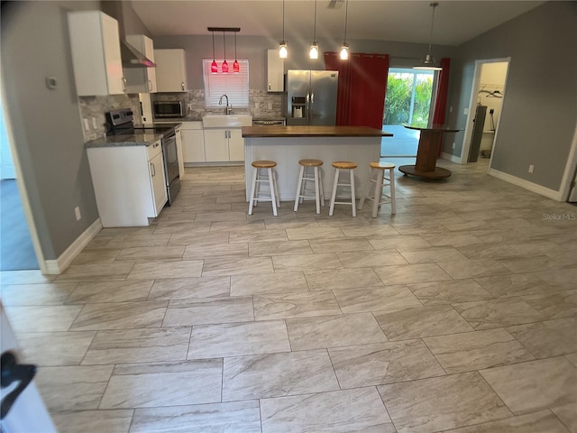 kitchen with appliances with stainless steel finishes, a breakfast bar, white cabinetry, sink, and a center island