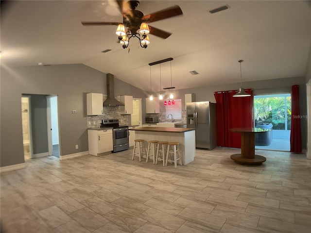 kitchen with sink, white cabinetry, a kitchen breakfast bar, stainless steel appliances, and wall chimney range hood