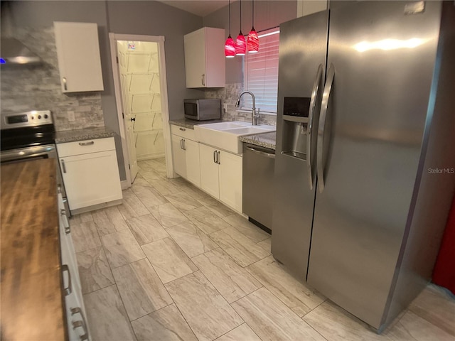 kitchen featuring appliances with stainless steel finishes, pendant lighting, white cabinetry, sink, and backsplash