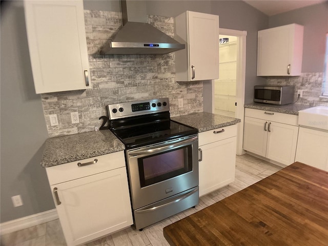 kitchen with tasteful backsplash, appliances with stainless steel finishes, white cabinets, and wall chimney exhaust hood