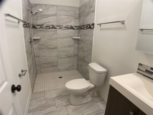 bathroom with vanity, toilet, and a tile shower