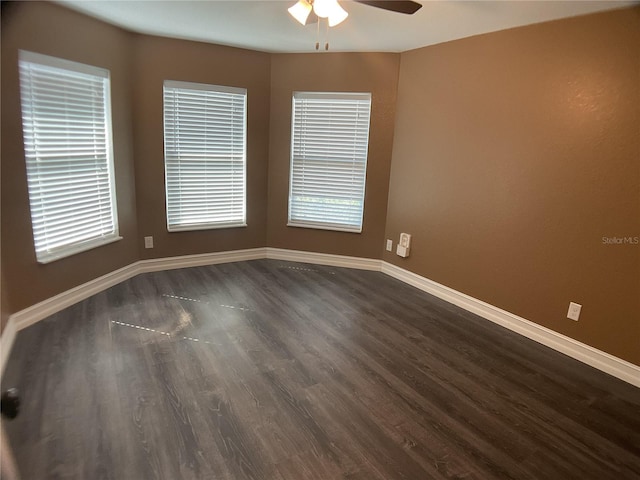 empty room featuring ceiling fan, a healthy amount of sunlight, and dark hardwood / wood-style flooring