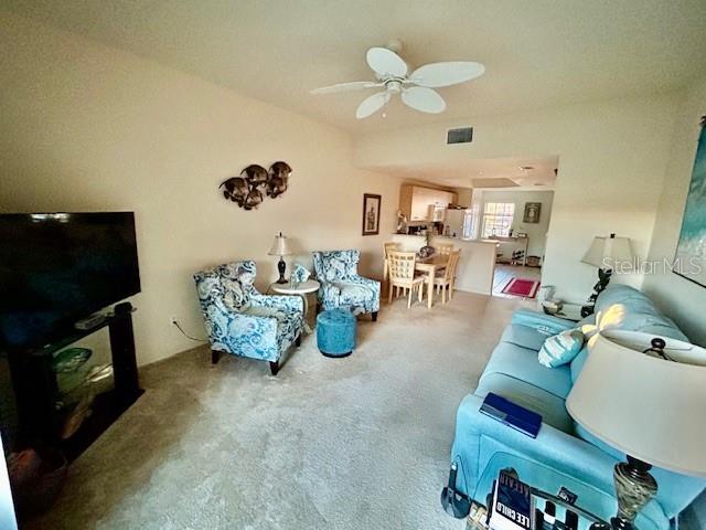 living area featuring a ceiling fan, visible vents, and carpet flooring