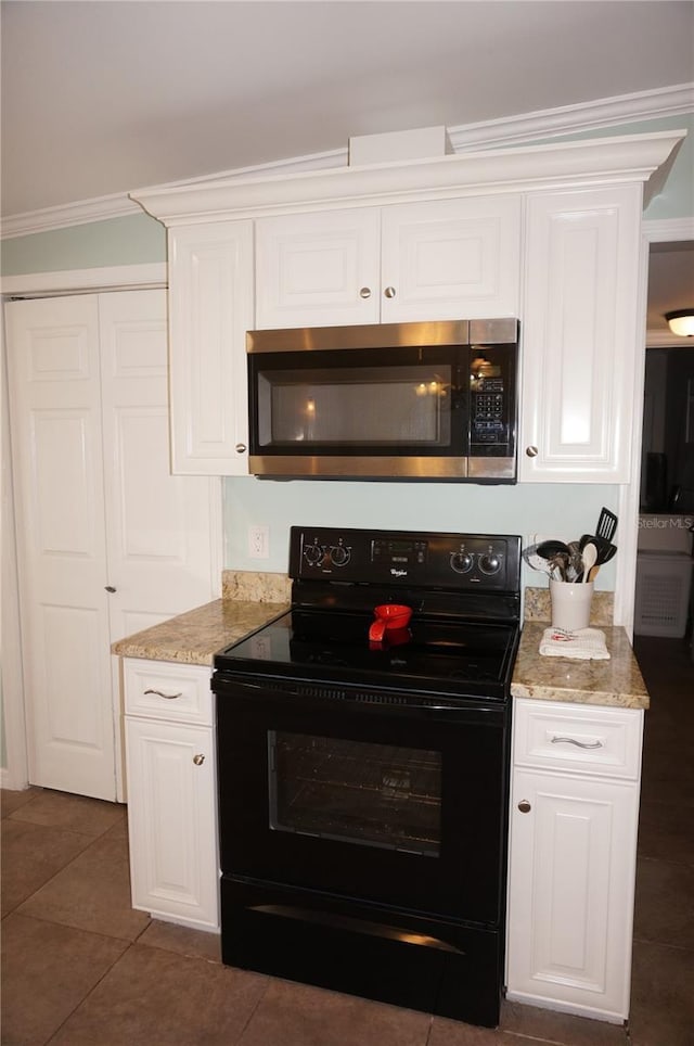 kitchen with black electric range oven, crown molding, dark tile patterned flooring, light stone countertops, and white cabinets