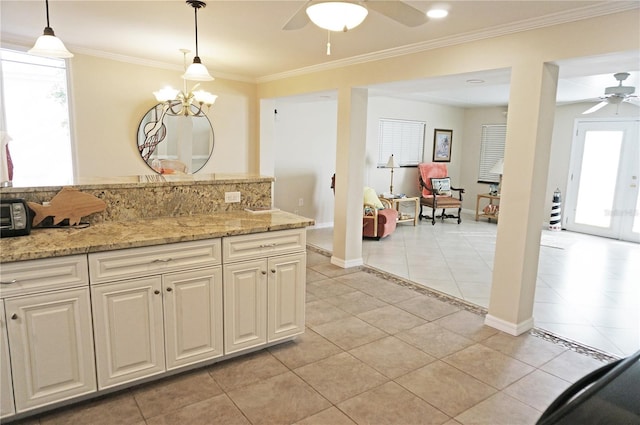 kitchen featuring light tile patterned flooring, crown molding, decorative light fixtures, ceiling fan, and light stone countertops