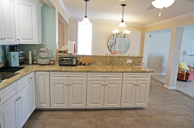 kitchen with light tile patterned flooring, decorative light fixtures, white cabinetry, ornamental molding, and light stone countertops