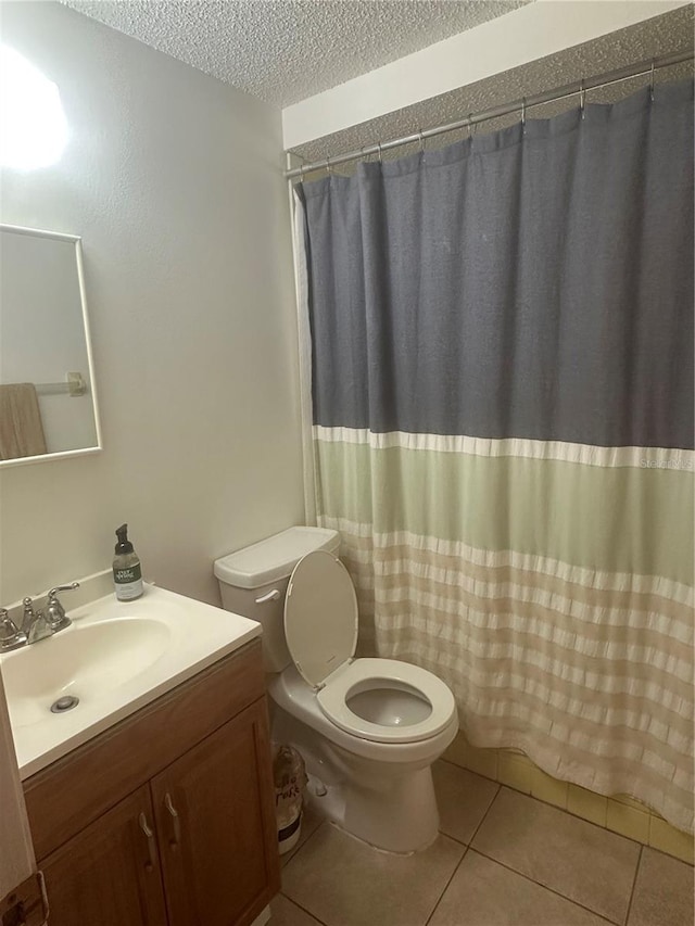 bathroom featuring curtained shower, tile patterned flooring, vanity, toilet, and a textured ceiling