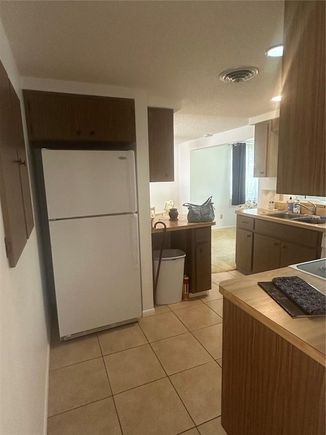 kitchen featuring white fridge, sink, and light tile patterned floors