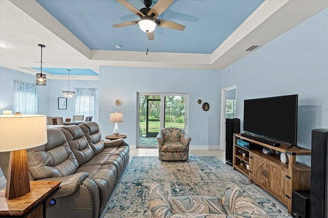 tiled living room featuring a raised ceiling and ceiling fan