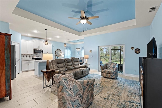 living room with a tray ceiling and ceiling fan