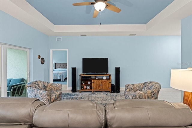 living room with a raised ceiling and ceiling fan