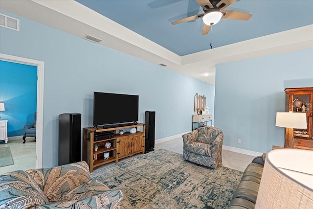 living room with a raised ceiling and ceiling fan