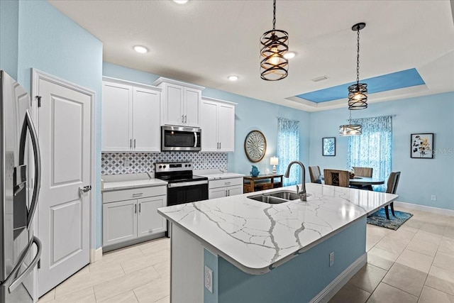 kitchen featuring decorative light fixtures, stainless steel appliances, and an island with sink