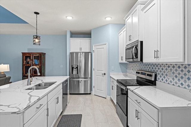 kitchen featuring sink, white cabinetry, decorative light fixtures, appliances with stainless steel finishes, and an island with sink