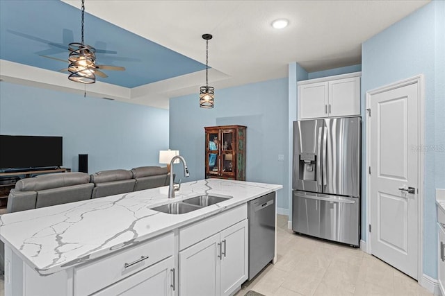 kitchen with sink, appliances with stainless steel finishes, an island with sink, pendant lighting, and white cabinets