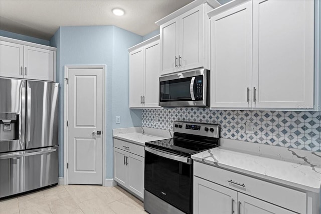 kitchen with appliances with stainless steel finishes, white cabinets, decorative backsplash, light tile patterned floors, and light stone counters