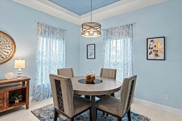 tiled dining area featuring a tray ceiling