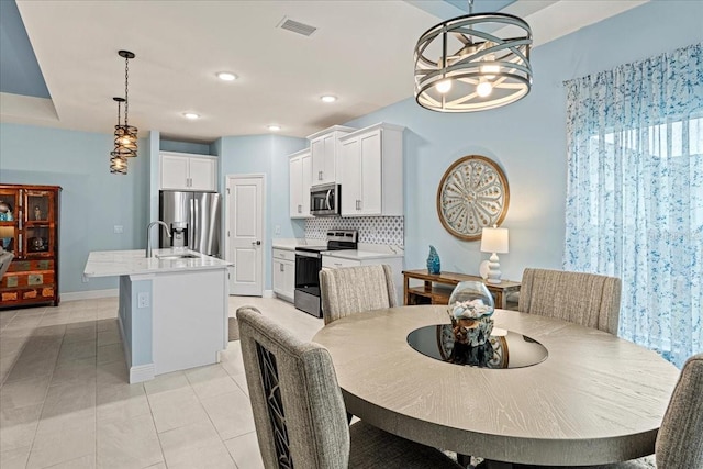 tiled dining space featuring an inviting chandelier and sink