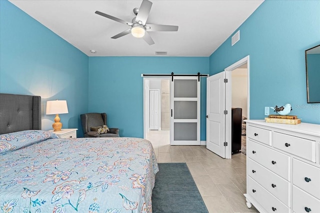 bedroom with light tile patterned floors, a barn door, and ceiling fan