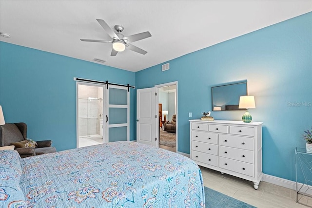 bedroom featuring a barn door, ceiling fan, and ensuite bath