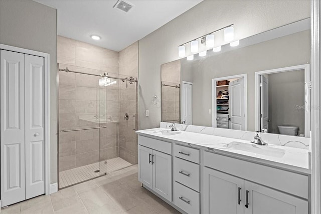 bathroom featuring tile patterned flooring, vanity, toilet, and walk in shower