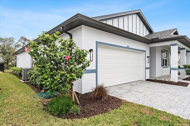 view of side of home featuring a garage, cooling unit, and a lawn