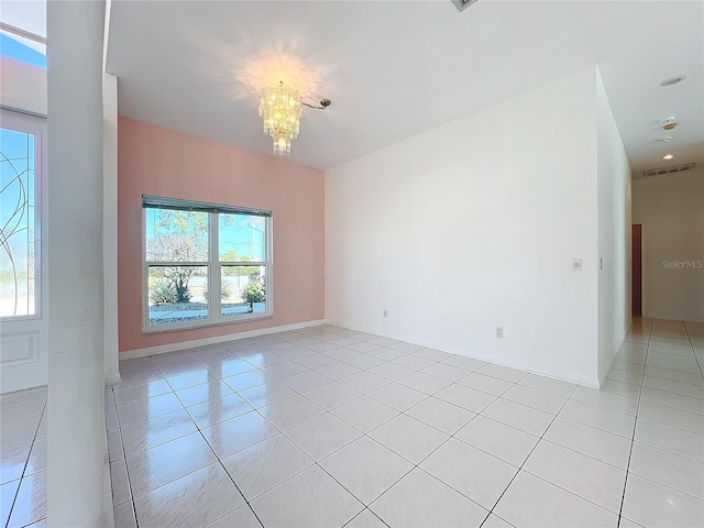 tiled empty room featuring a chandelier