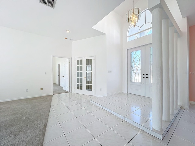 tiled entrance foyer featuring french doors, a notable chandelier, and a high ceiling