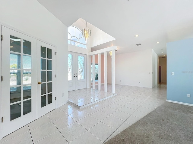 interior space featuring an inviting chandelier, a towering ceiling, and french doors