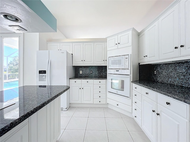 kitchen with white cabinetry, white appliances, decorative backsplash, and dark stone countertops