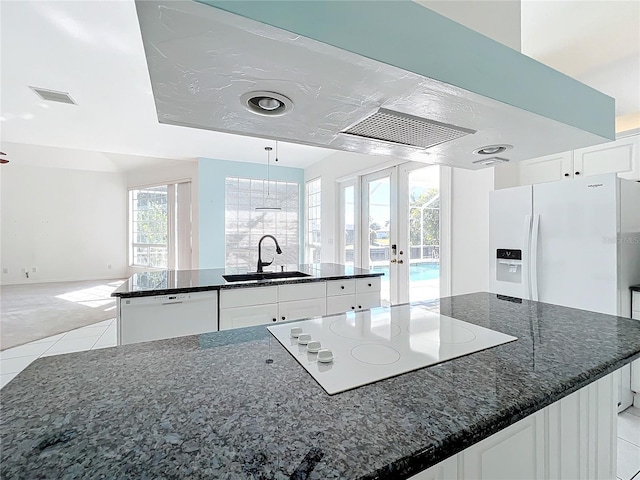 kitchen with sink, white cabinetry, dark stone countertops, a large island with sink, and white appliances