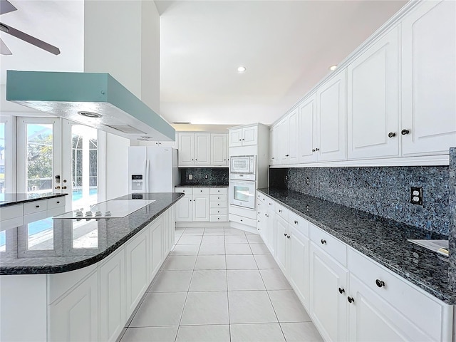 kitchen with range hood, fridge with ice dispenser, white oven, and white cabinets