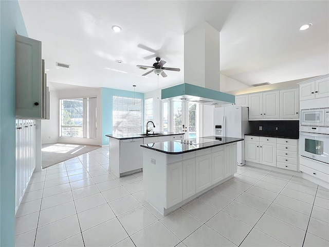 kitchen featuring sink, white appliances, light tile patterned floors, white cabinetry, and a kitchen island