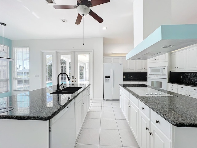 kitchen featuring white cabinets, white appliances, sink, and a large island with sink