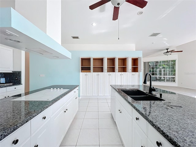 kitchen featuring sink, white electric cooktop, ventilation hood, white cabinets, and dark stone counters