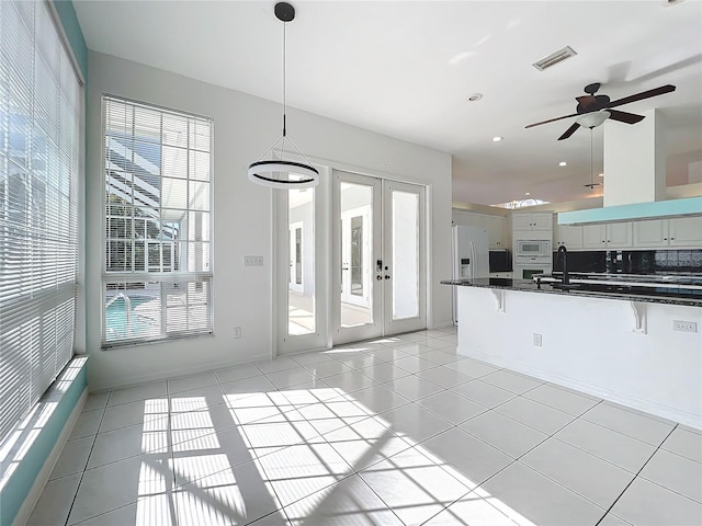 kitchen with french doors, a breakfast bar, pendant lighting, white appliances, and white cabinets