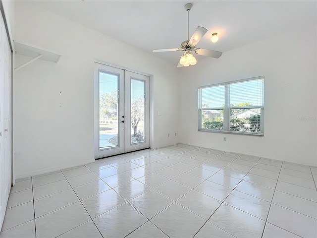 tiled empty room featuring french doors and ceiling fan