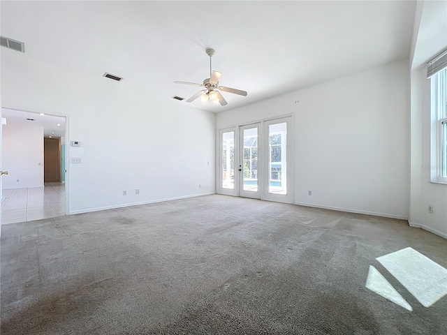 carpeted spare room featuring ceiling fan and french doors