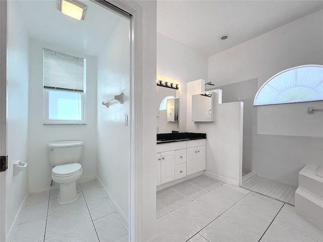 bathroom with vanity, tile patterned floors, toilet, and tiled shower