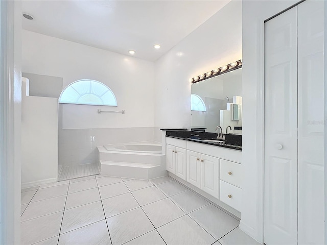 bathroom with tile patterned flooring, a tub to relax in, and vanity