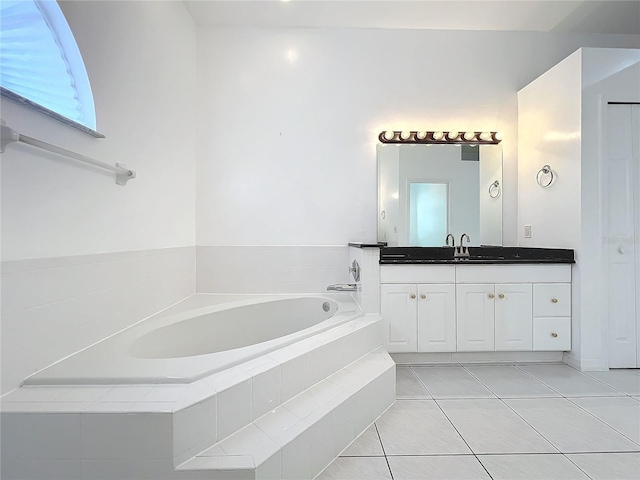 bathroom with tile patterned flooring, vanity, and tiled bath