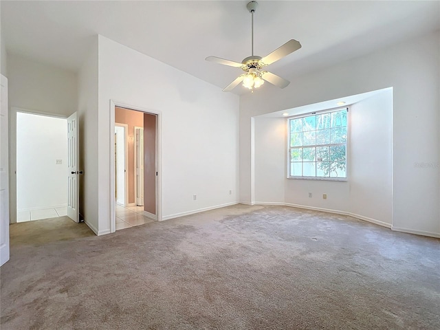 spare room with light carpet, a towering ceiling, and ceiling fan