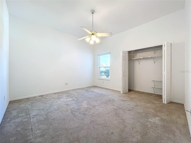 unfurnished bedroom featuring ceiling fan, lofted ceiling, carpet flooring, and a closet