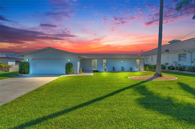 ranch-style house featuring a garage and a lawn