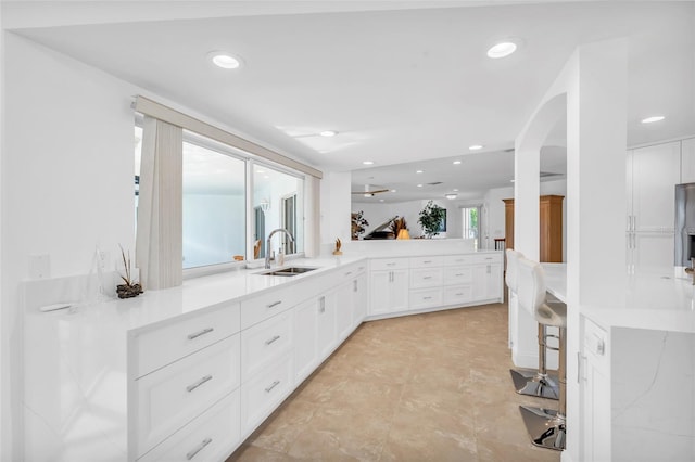 kitchen featuring white cabinetry, sink, kitchen peninsula, and a healthy amount of sunlight