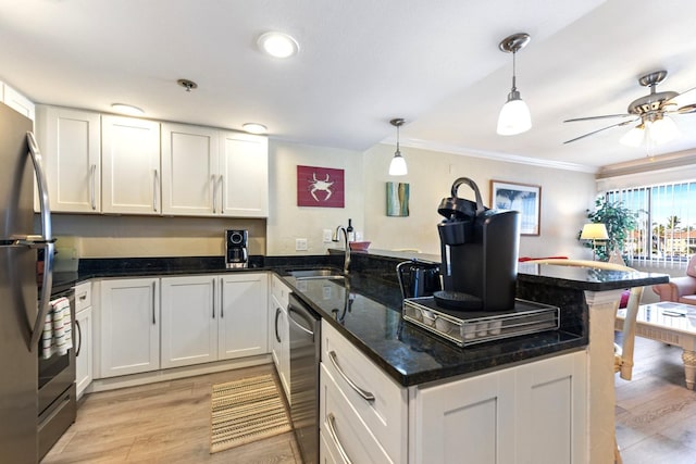 kitchen with decorative light fixtures, white cabinetry, sink, dark stone countertops, and kitchen peninsula