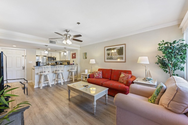 living room with ornamental molding, ceiling fan, and light wood-type flooring