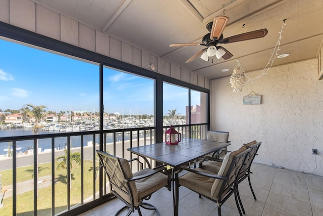 unfurnished sunroom with ceiling fan and a water view