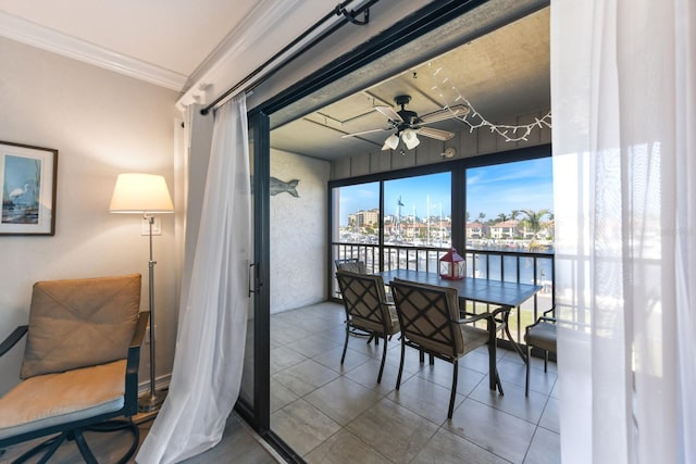 dining room with tile patterned flooring, ornamental molding, ceiling fan, and a water view